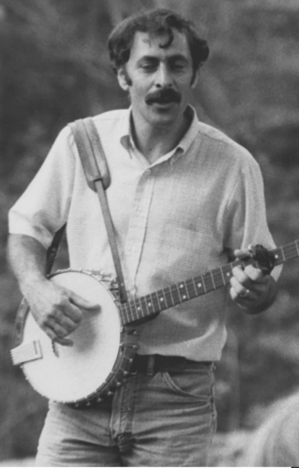 Richard Herman as a young man, playing a five-string banjo outdoors.